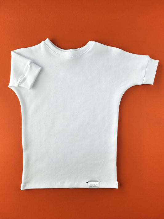 White grow-with-me t-shirt for kids, made from soft organic cotton with a stretchy, foldable waistband. Ethically made in Canada for a sustainable and comfy fit.