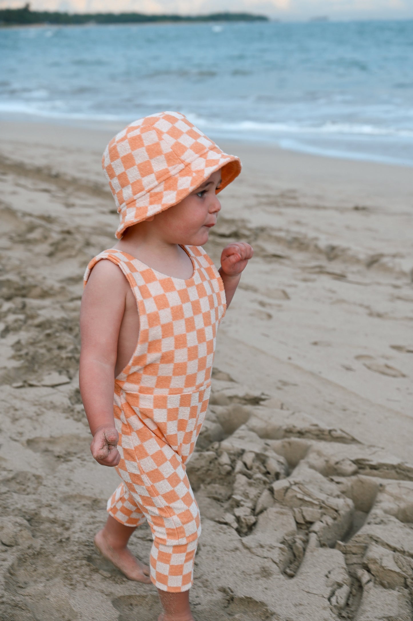 Orange checkered overalls made in Canada with eco-friendly fabric designed to grow with your child