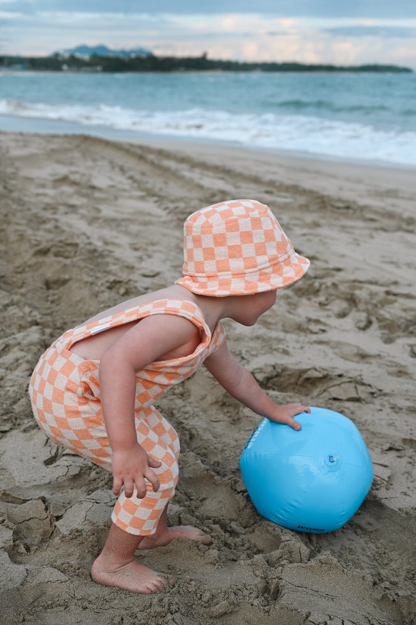 Orange checkered overalls made in Canada with eco-friendly fabric designed to grow with your child